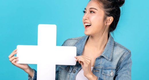 Image d'une femme asiatique souriant tenant un signe plus dans ses mains