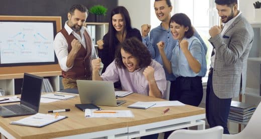 Equipe de jeunes collaborateurs célébrant une réussite devant un ordinateur